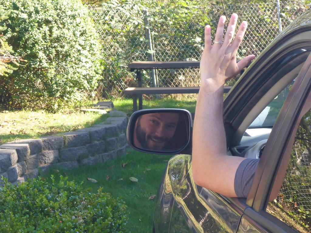 Jeremy sitting in front seat of truck waving out window.