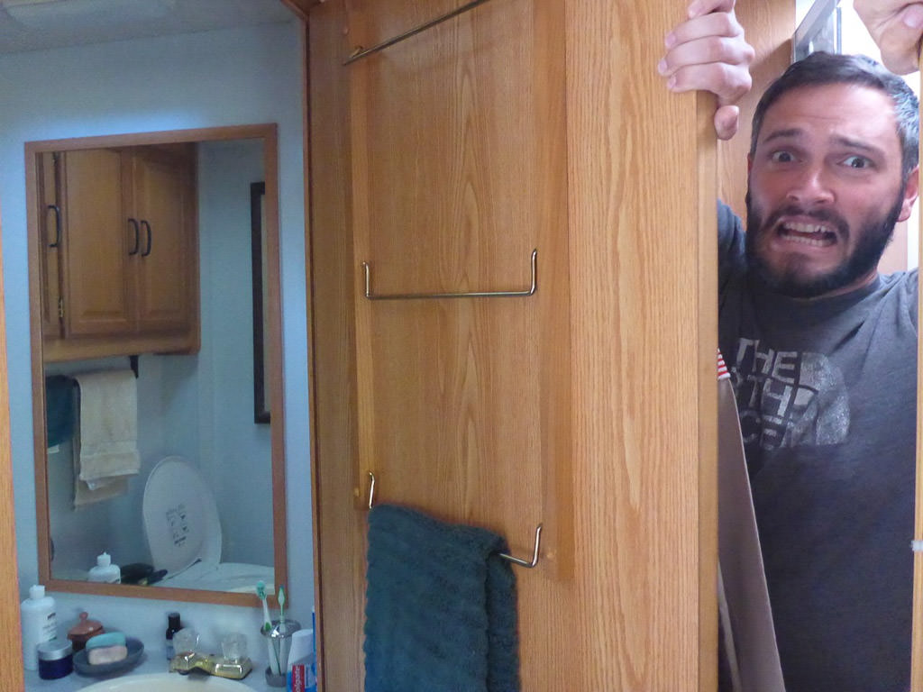 Jeremy making a face as he tries to squeeze by the open bathroom door.