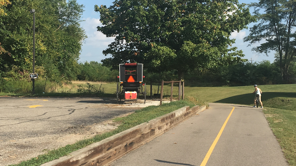 Horse cart parked in parking lot and biker going by drive-thru