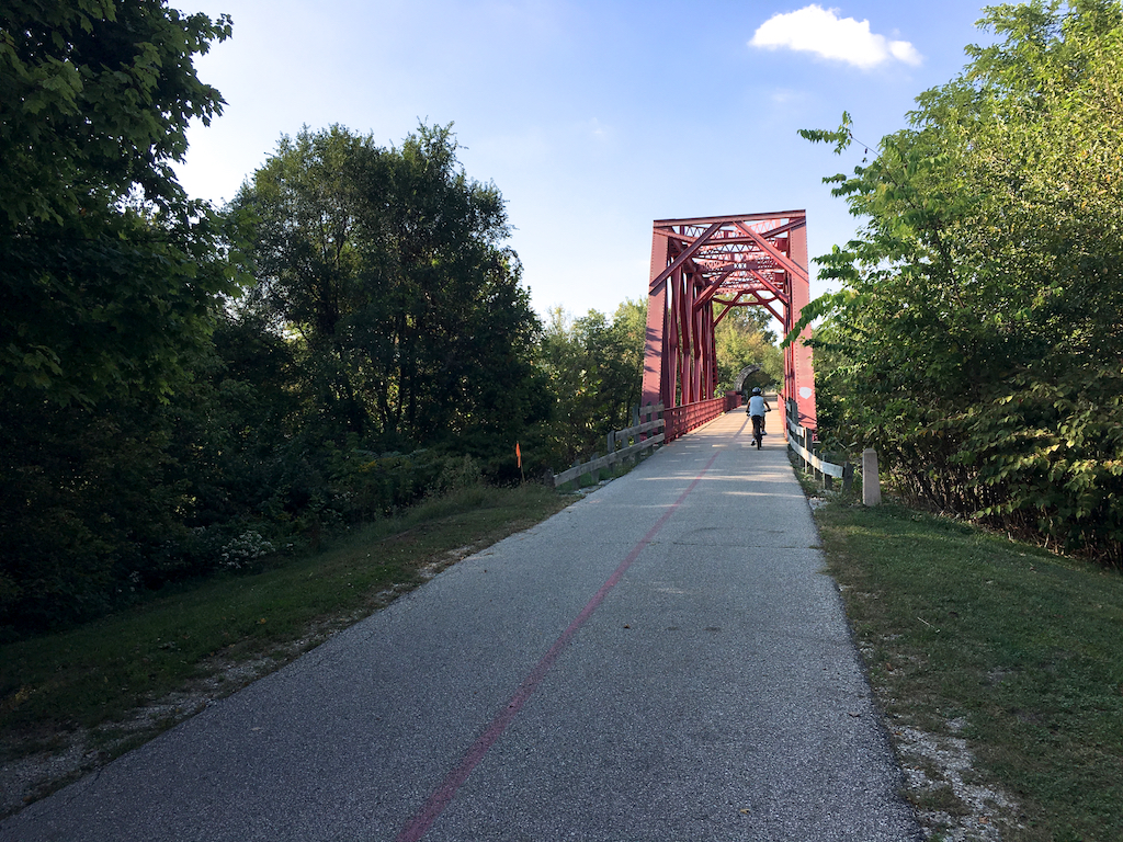 Biker about to cross red bridge on Monon Trail