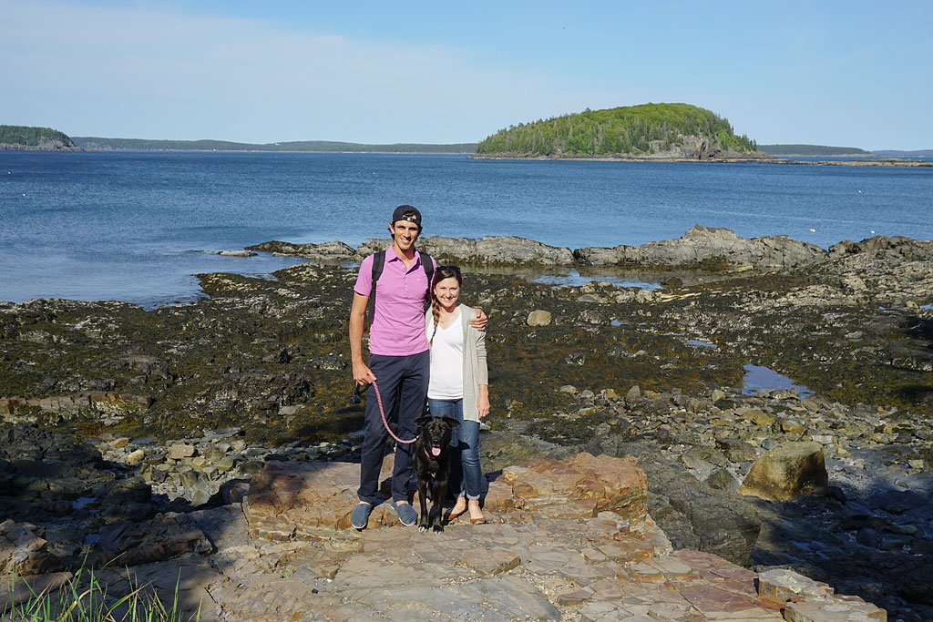 Jordan, Brittany, and Ella standing on rocks along the shore. 