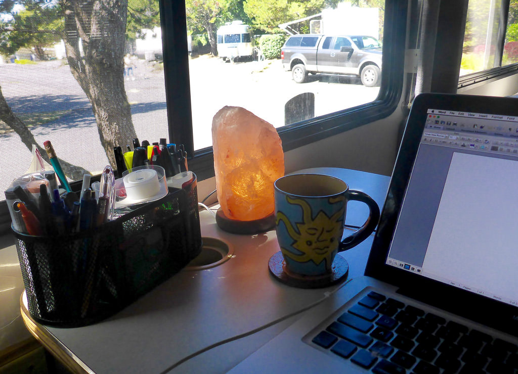 Pencil holder, lamp, coffee mug, and computer on RV dinette.