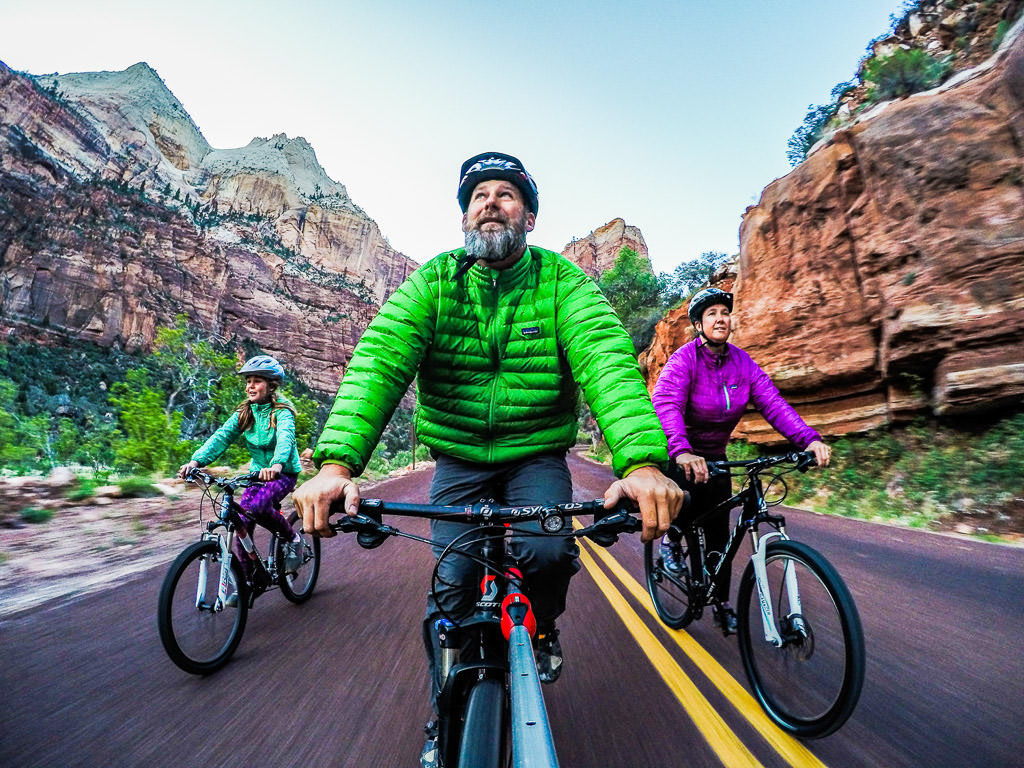 Abby, Peter, and Kathy Holcombe riding bikes down road