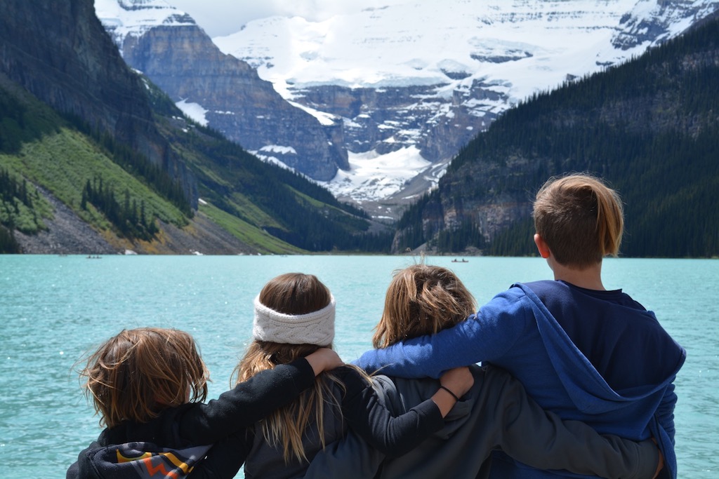 Four kids standing facing lake and mountains