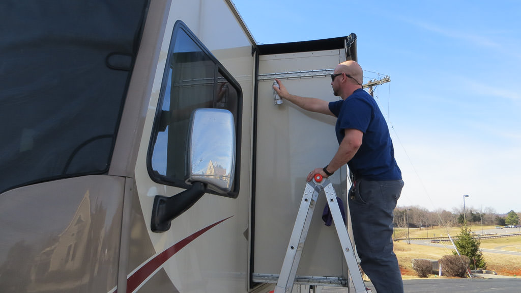 Kenny on ladder doing maintenance on slide of RV