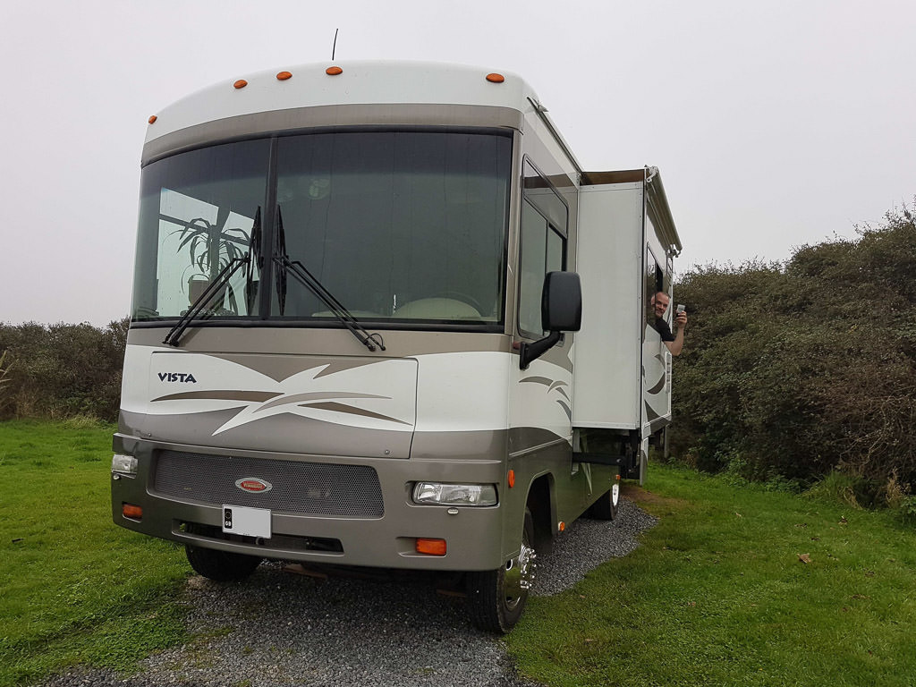 Winnebago Vista parked in campsite with man sticking head out the window.