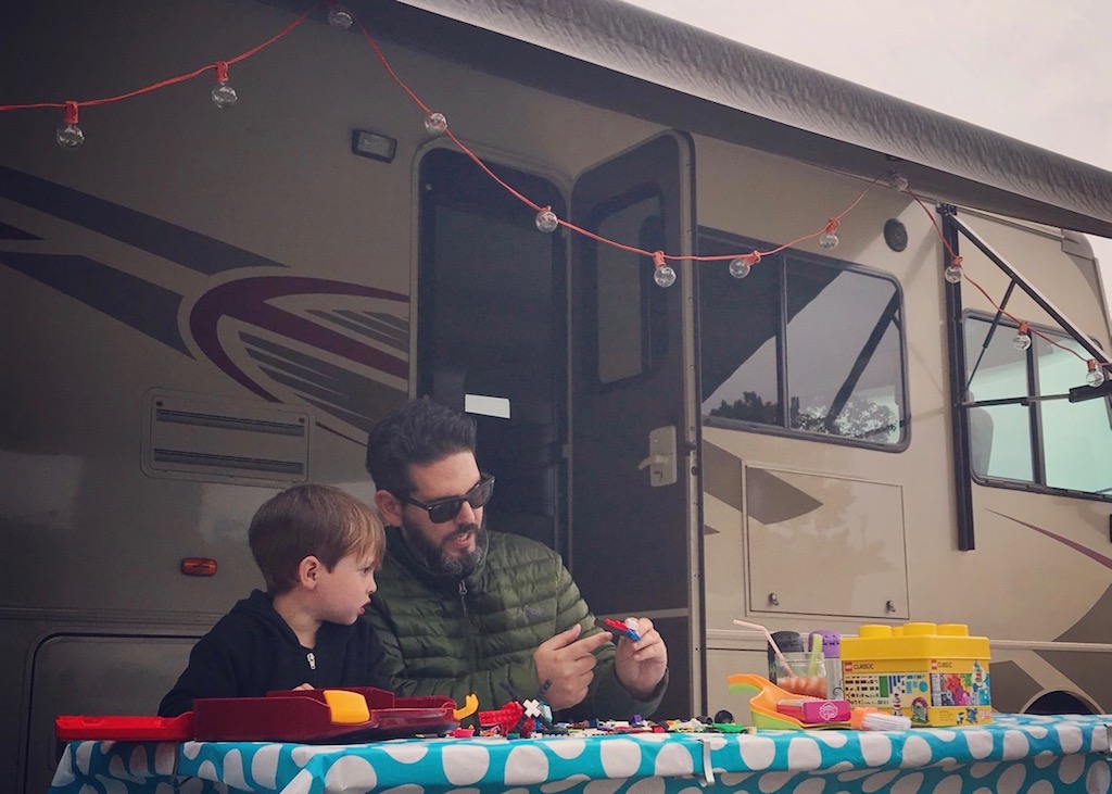 David sitting with child at picnic table playing with Legos