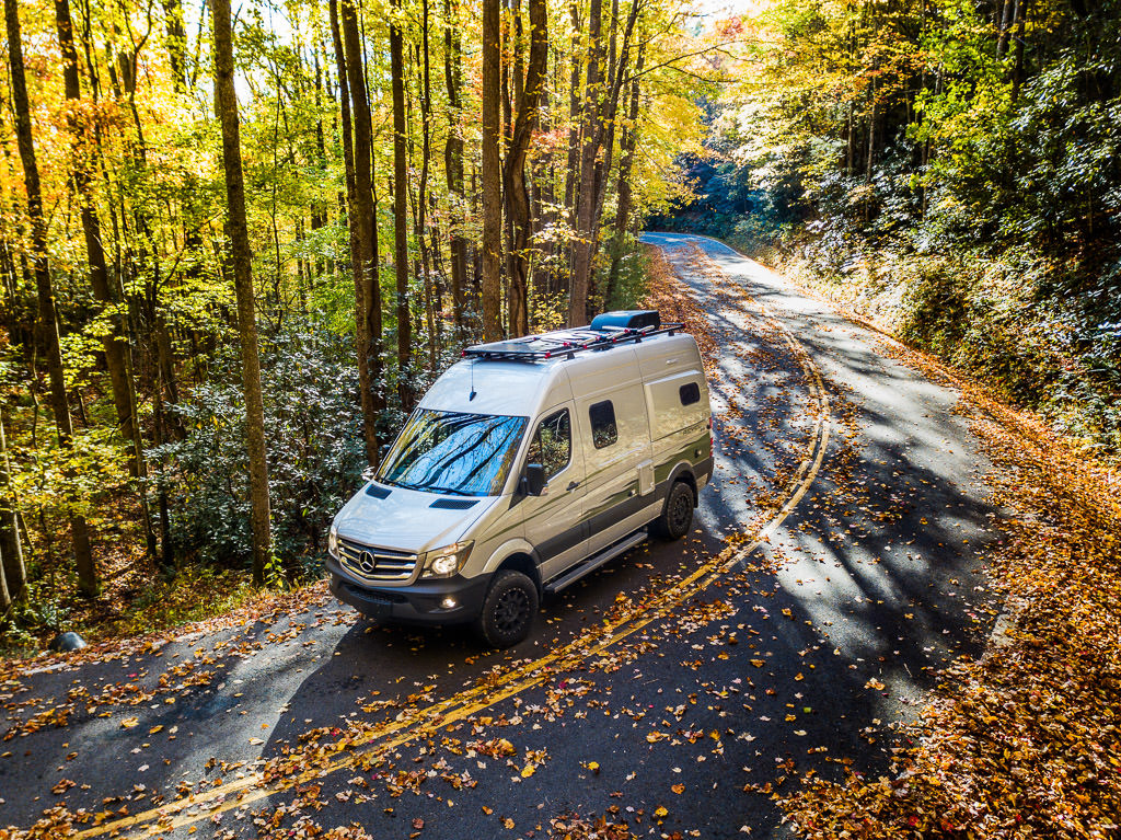 Winnebago driving on a road through the Fall foliage.