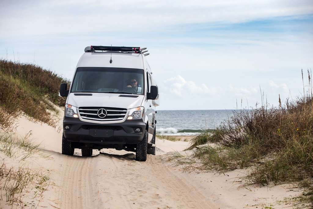 Kathy driving the Winnebago away from the beach on a sandy path.