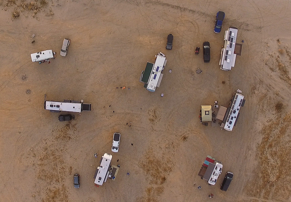 Aerial shot of seven RVs parked large gravel lot