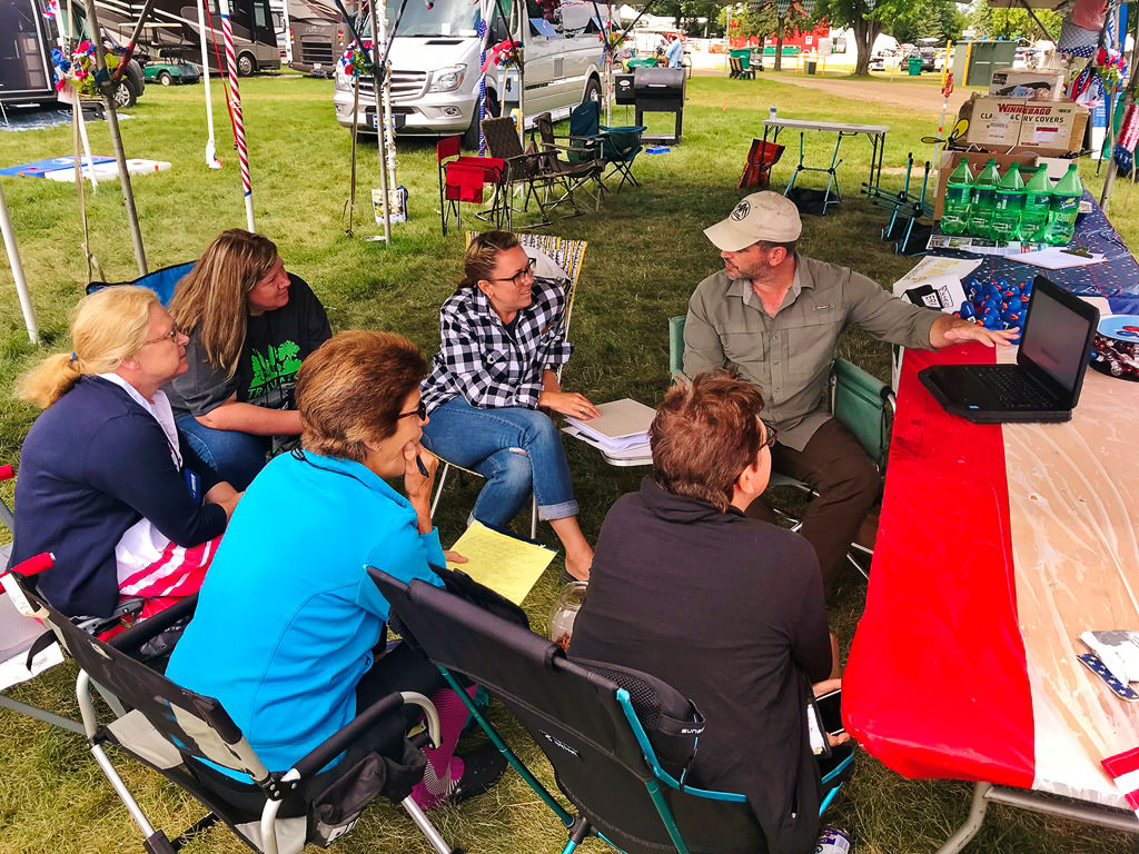 A few people gathered under a tent at Grand National Rally
