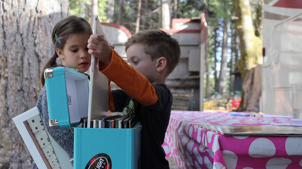Two kids looking through a box of records.