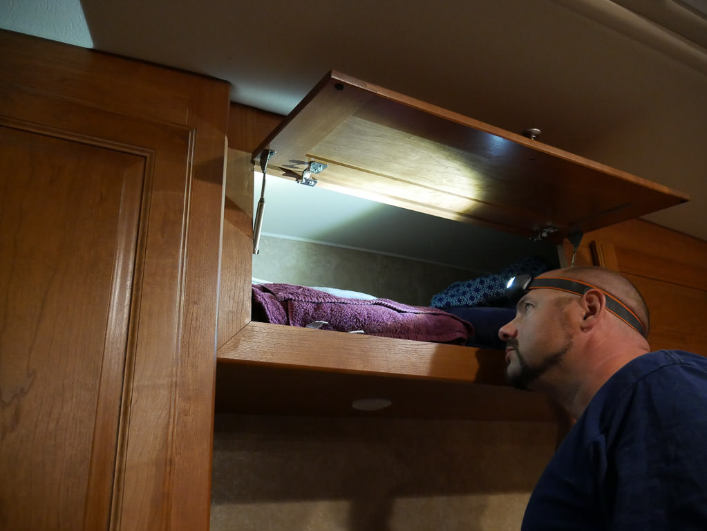 Kenny wearing head lamp looking in overhead bin