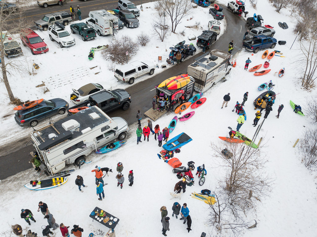 Winnebago View with trailer attached parked on the snow among other vehicles, RVs, and many people gathered in winter gear.