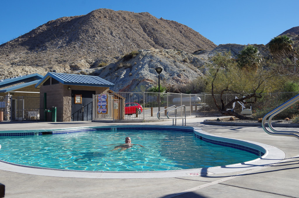 Man in a pool with rough landscape surrounding.