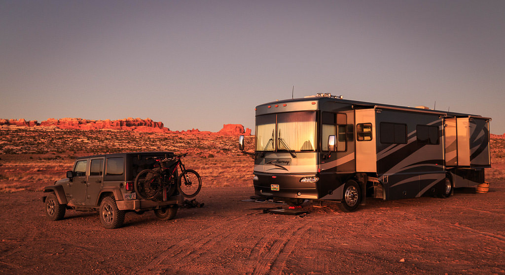 Journey parked in dessert next to tow car and bike 
