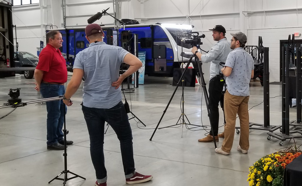 Film crew filming Russ Garfin among product display.