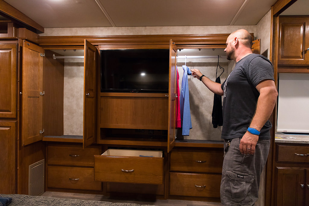 Kenny hanging clothes in the closet space in the back bedroom.