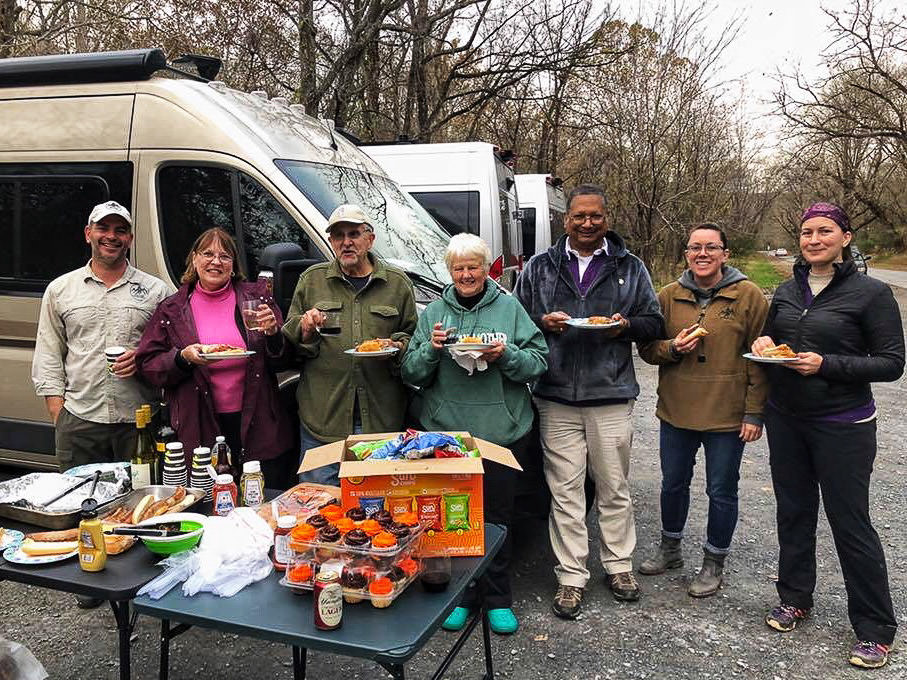 Travato group gathered in front of Warrior Expeditions Travato holding plates of food