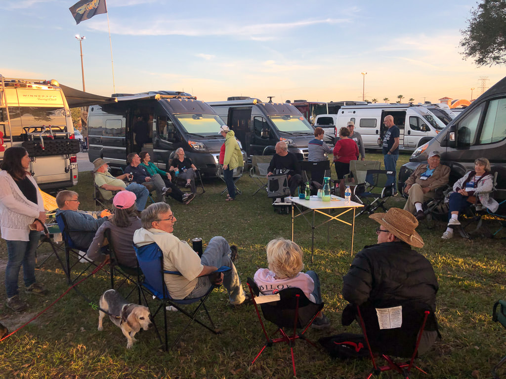 Group of people socializing among Winnebago vans.