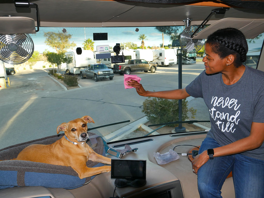 Sabrina cleaning inside of windshield. Belle is sitting on dash next to Sabrina