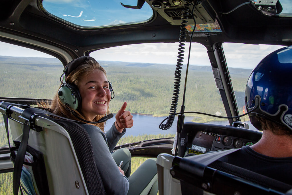Abby sitting shotgun in the helicopter with water and trees below.
