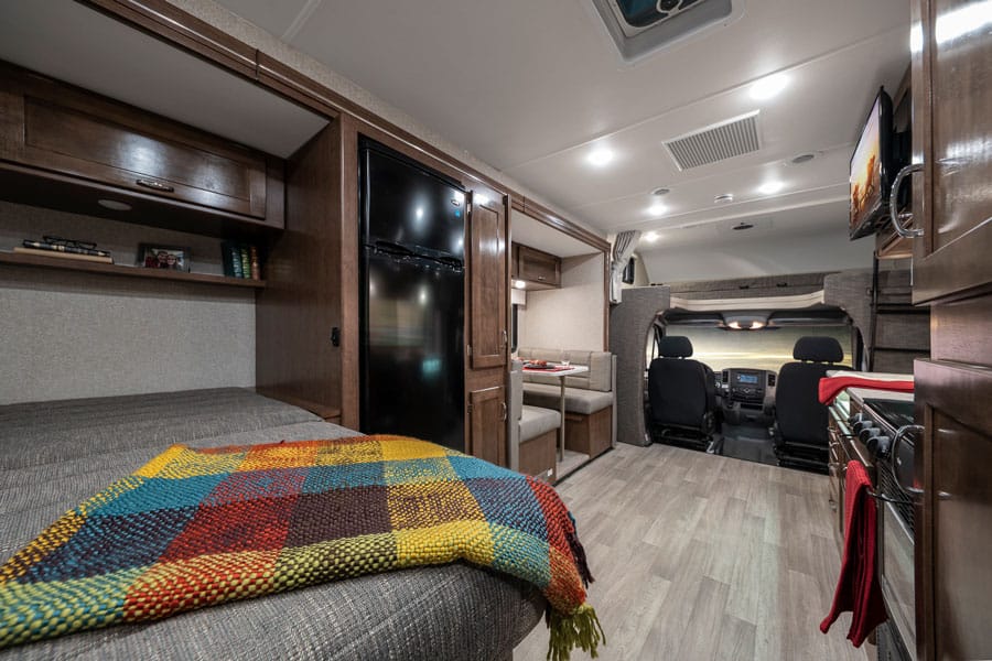 Winnebago Vita interior with bed, dinette nook, kitchenette and front cab. 