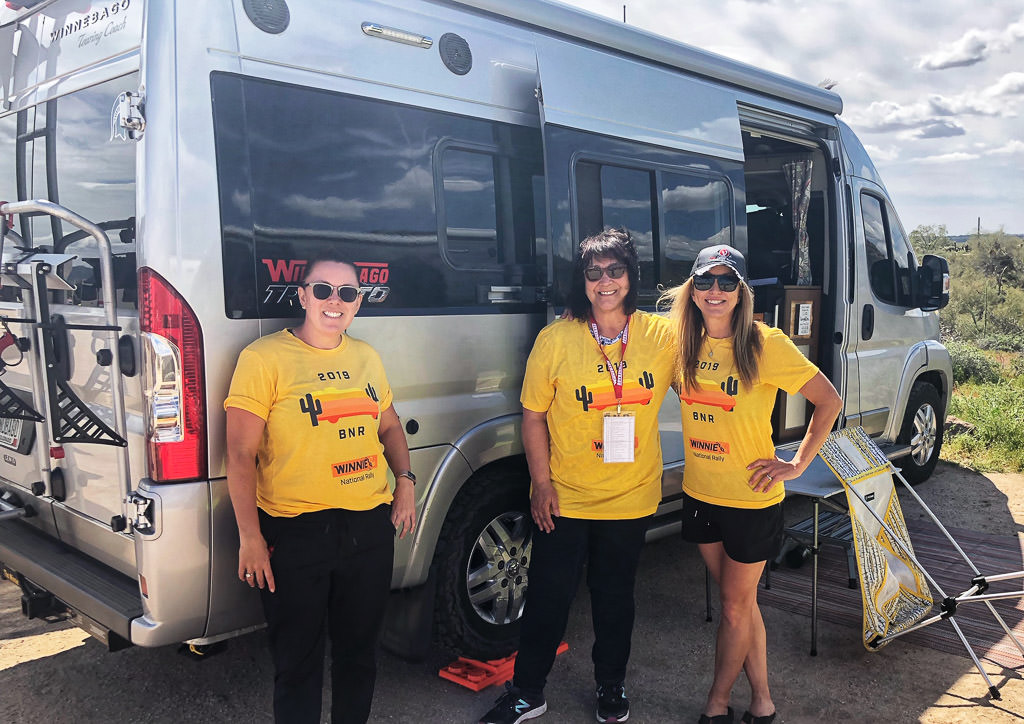 3 women in BNR shirts standing outside a Winnebago Travato.