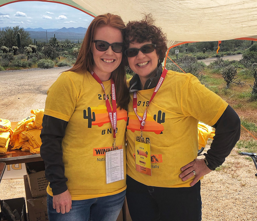 Two ladies helping at BNR registration tent smiling for the camera.