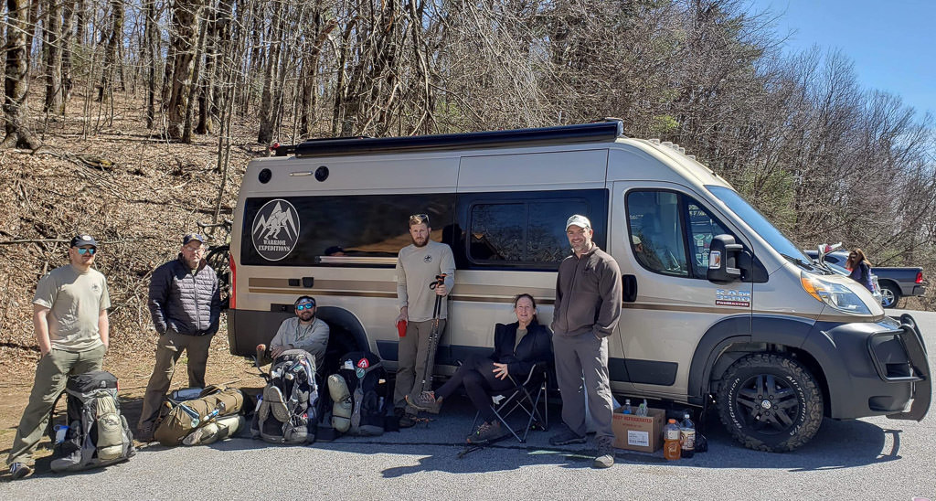 Warrior Expeditions participants sitting in front of Travato with gear