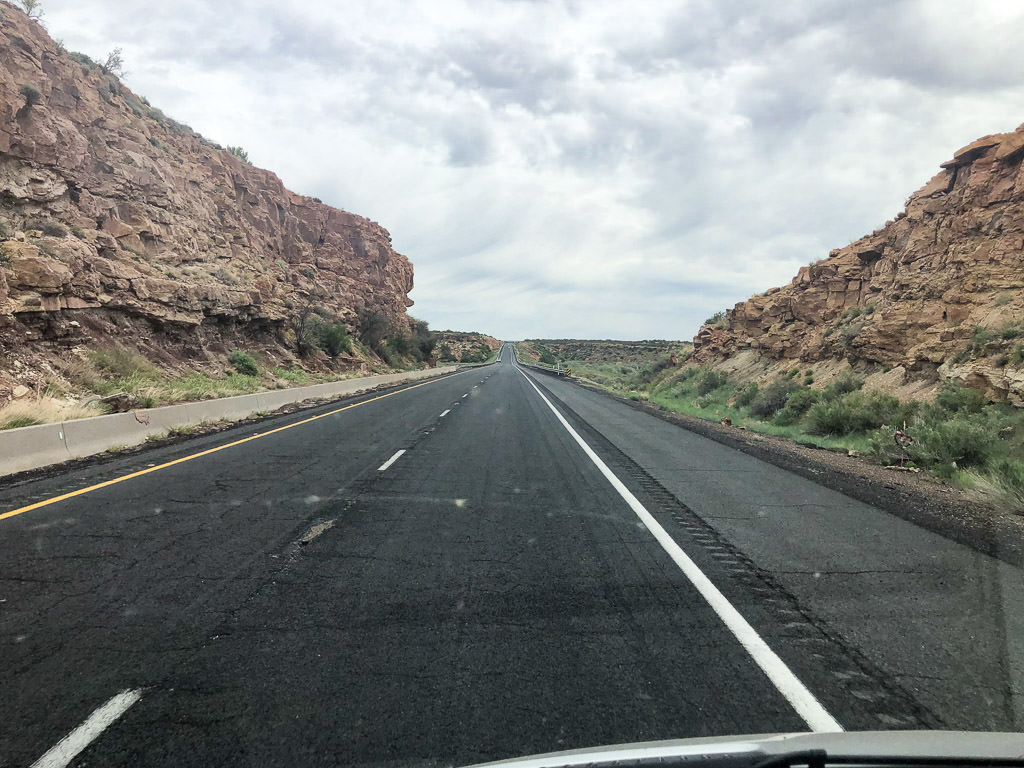 Open road ahead with rocky cliffs on either side.