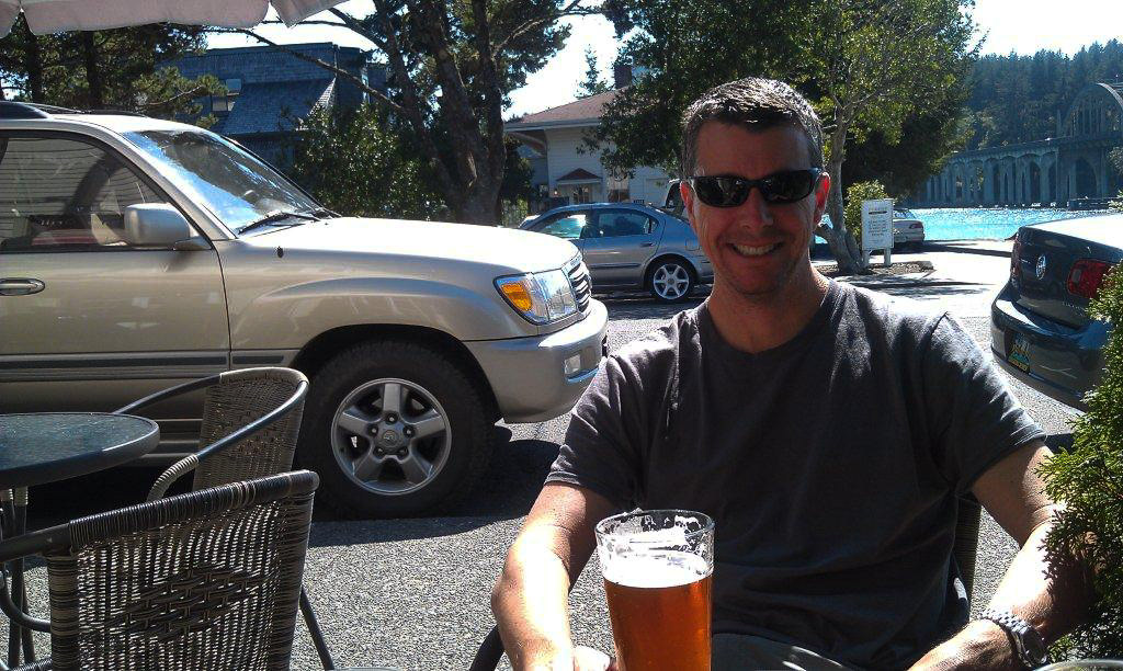 Man sitting at an outdoor table with a drink.