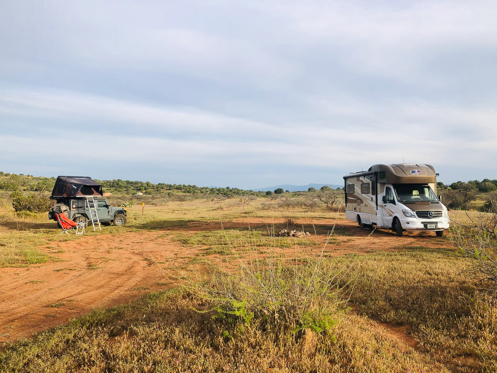 Winnebago View and Jeep parked in the middle of a field with no one else in sight.