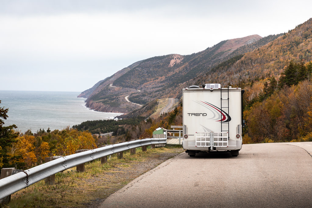 Winnebago Trend parked along the side of a road curving along the water and hills.