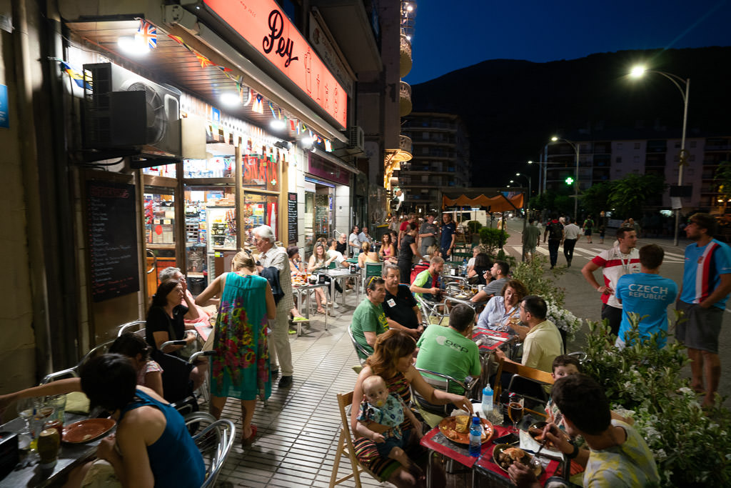 Crowd of people gathered at tables outside a restaurant. 