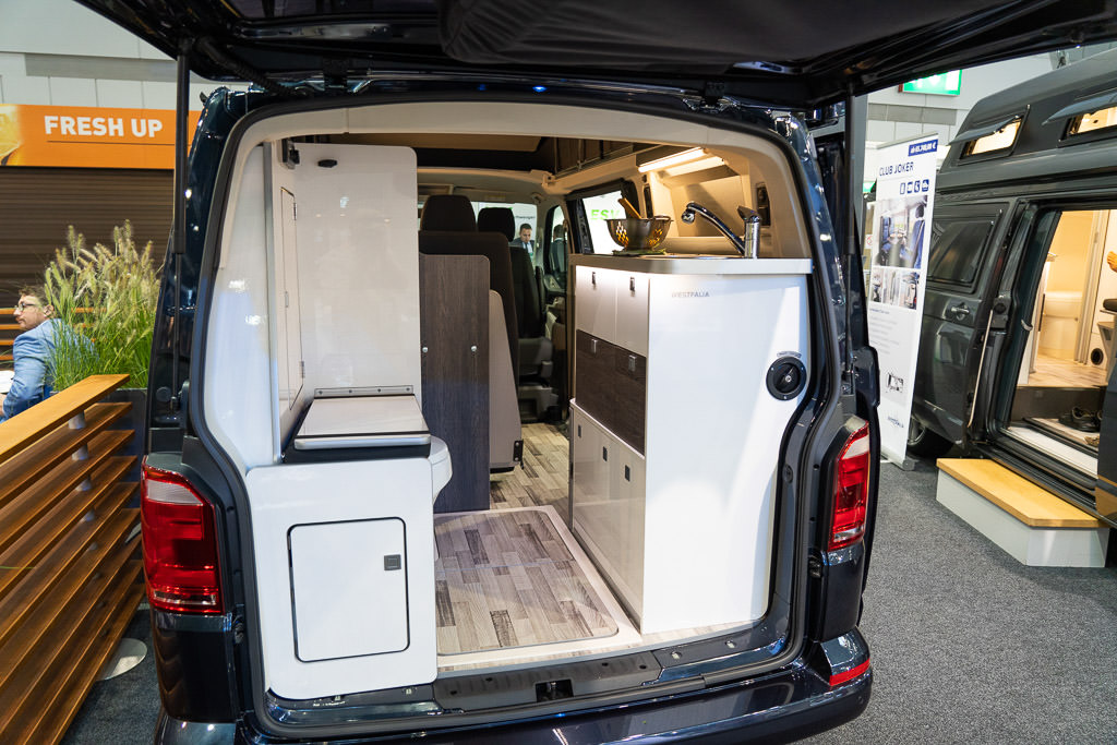 View from back of minivan camper with kitchen and toilet area visible.