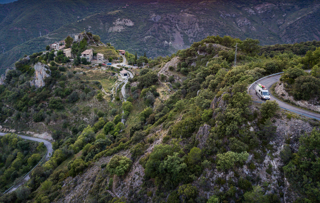 Winnebago Revel driving along winding narrow roads with small homes in view. 